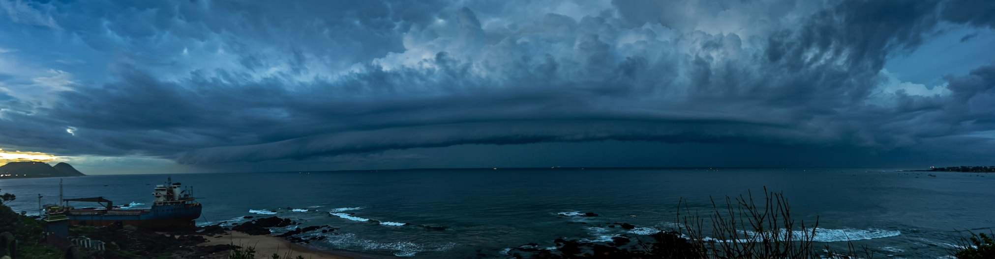 How do arcus clouds form over the coast, showing a dark, low-hanging shelf cloud stretching across a moody grey sky.