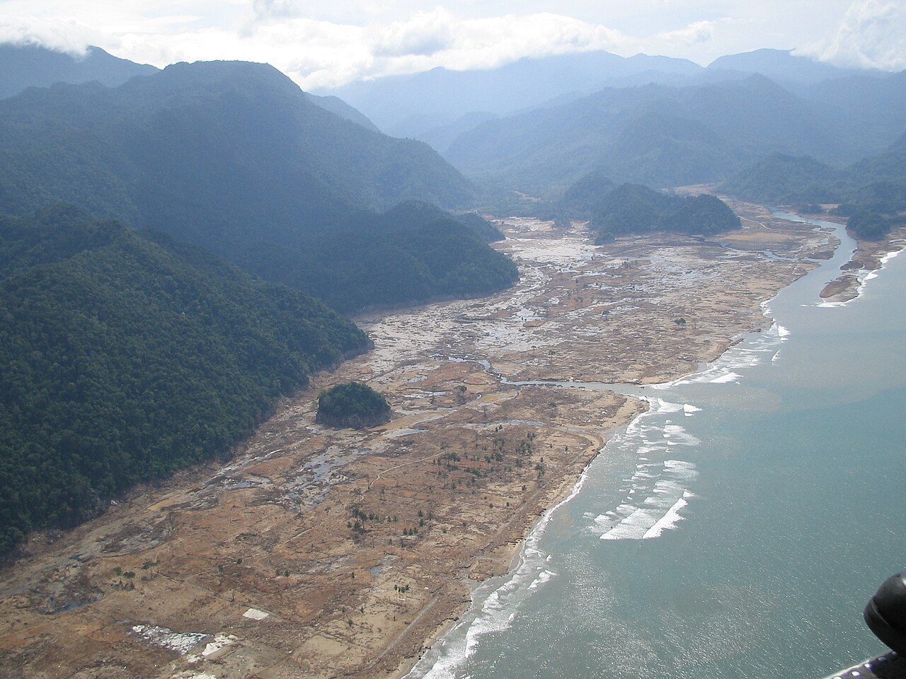 Aerial view of a coastline devastated by a tsunami, showing widespread debris and altered landscape from powerful waves. Aerial view of a coastline devastated by a tsunami, showing widespread debris and altered landscape from powerful waves.
