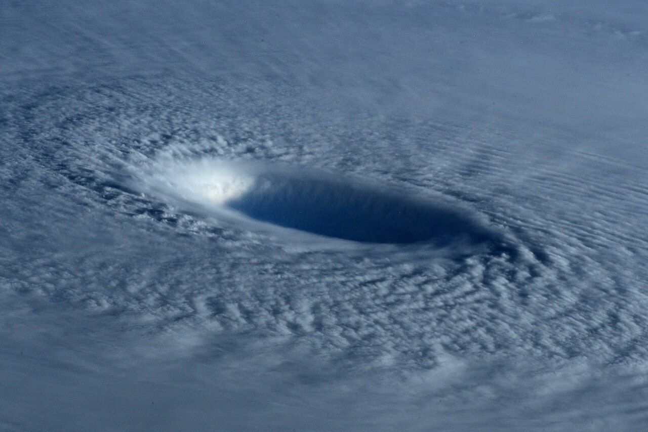 Aerial view of a hurricane's clear, calm eye surrounded by dense, swirling clouds, illustrating its formation.