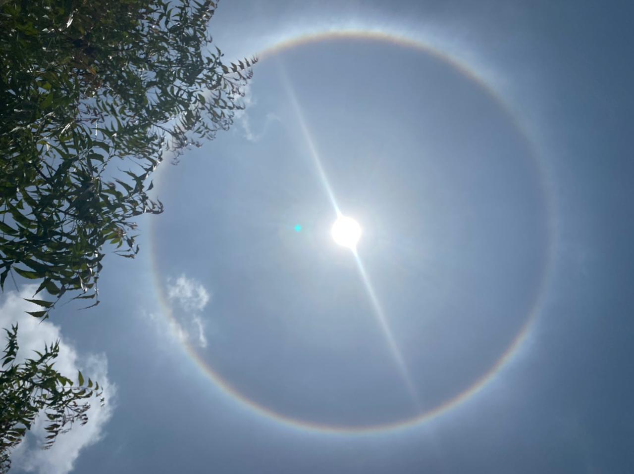 Bright sun in a blue sky with a distinct 22-degree halo, demonstrating ice crystal optics. Bright sun in a blue sky with a distinct 22-degree halo, demonstrating ice crystal optics.