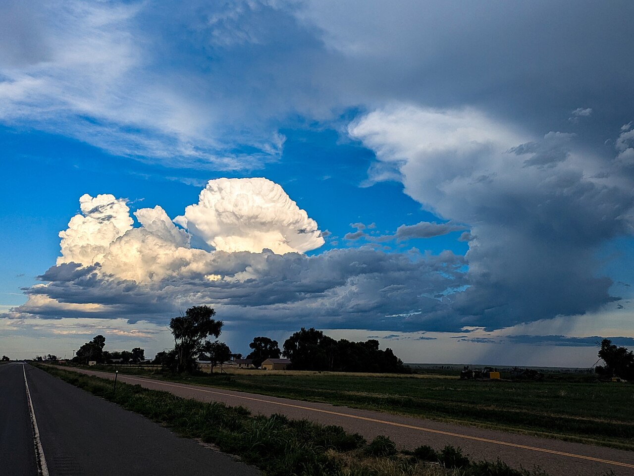 Developing cumulus clouds over a rural road, illustrating the atmospheric conditions for multicell thunderstorm formation. Developing cumulus clouds over a rural road, illustrating the atmospheric conditions for multicell thunderstorm formation.