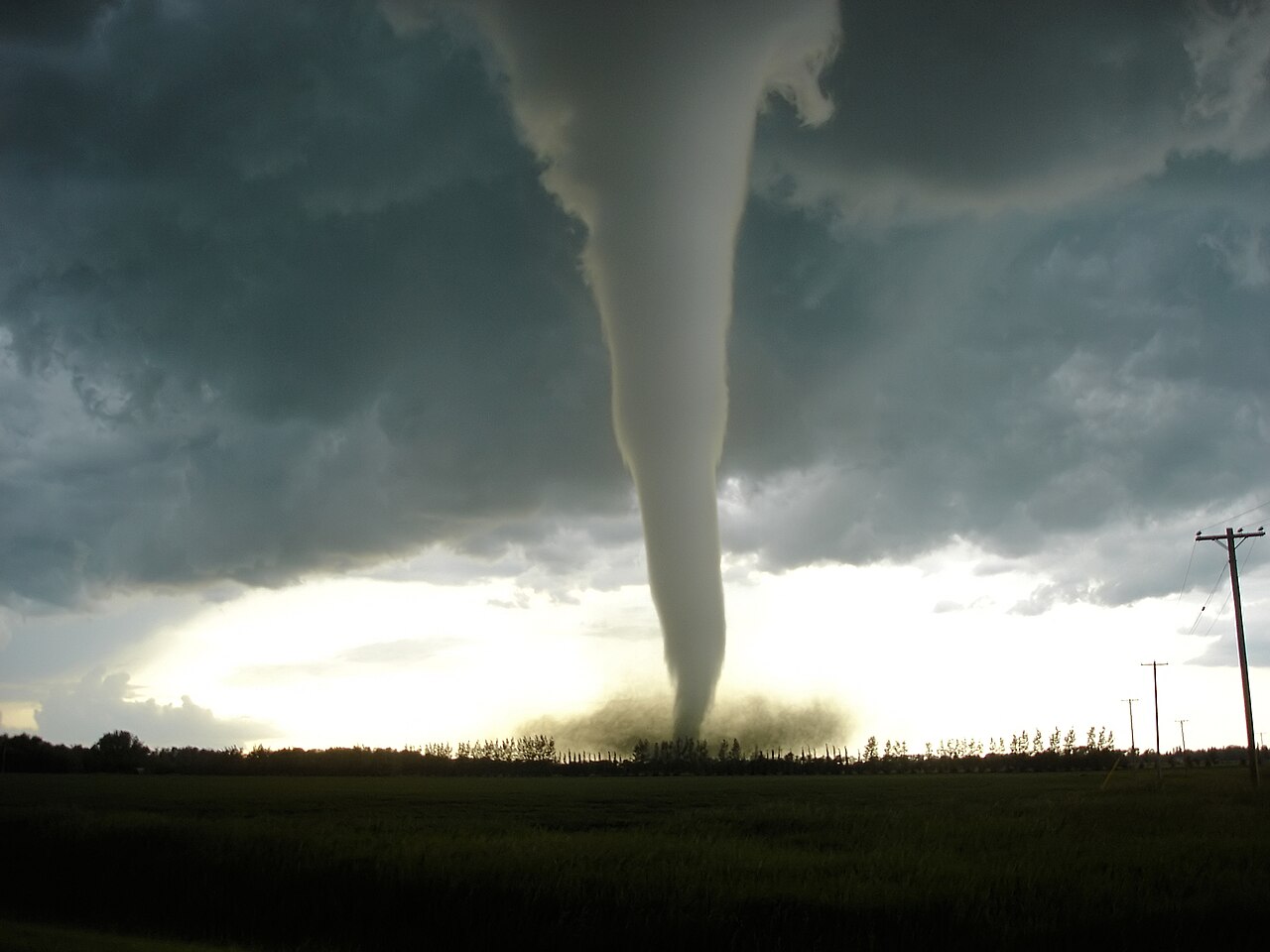 Powerful supercell tornado funnel cloud descending over a dark field, illustrating meteorological formation. Powerful supercell tornado funnel cloud descending over a dark field, illustrating meteorological formation.