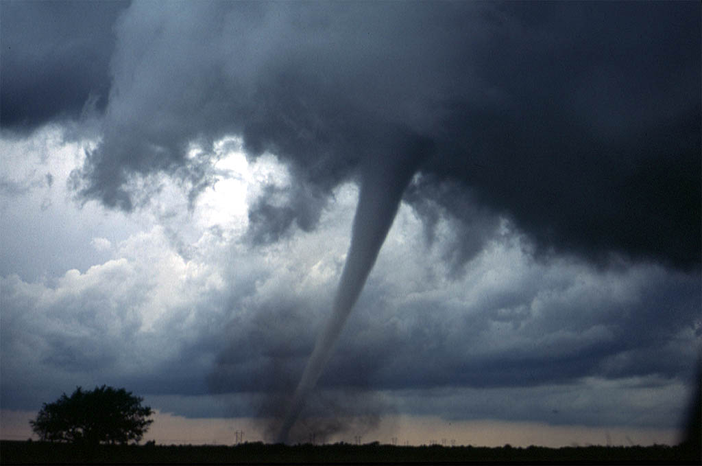 Powerful supercell tornado funnel cloud extending from dark storm clouds to the ground, illustrating formation. Powerful supercell tornado funnel cloud extending from dark storm clouds to the ground, illustrating formation.