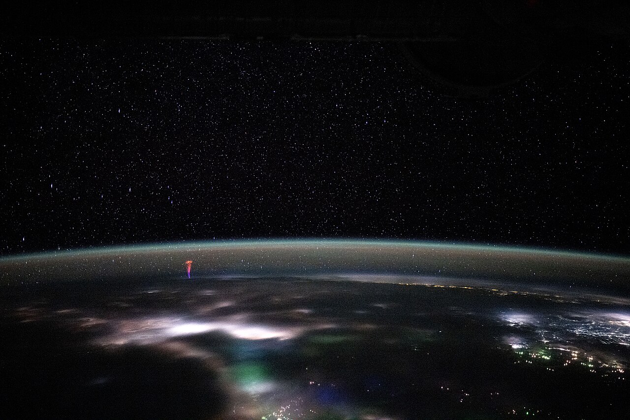 Red sprite lightning, a red-purple flash, shoots upward from Earth's atmosphere into the starry night sky. Red sprite lightning, a red-purple flash, shoots upward from Earth's atmosphere into the starry night sky.