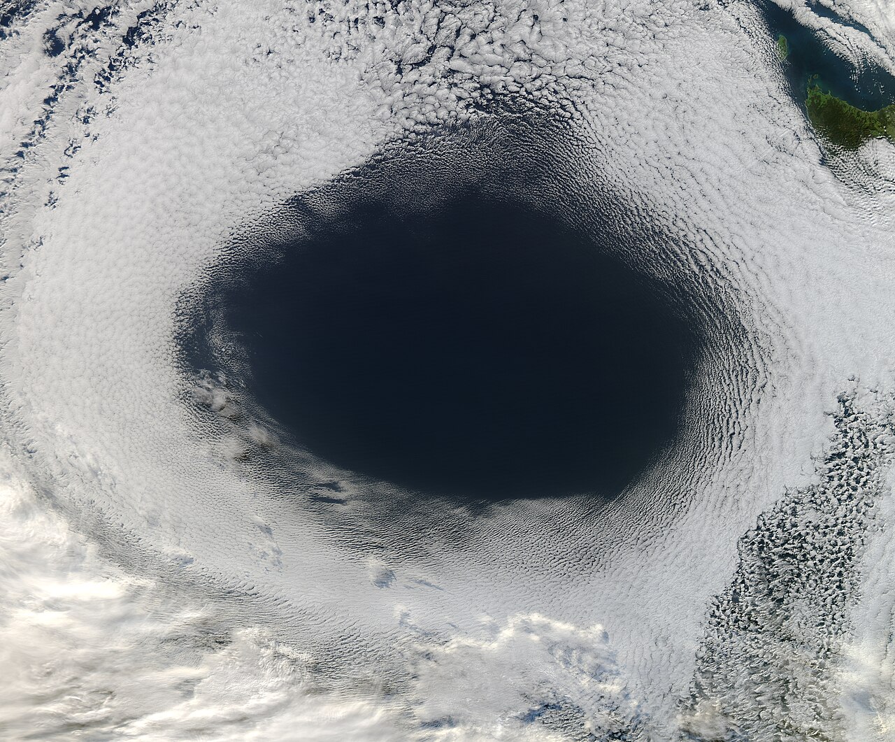 Satellite view of a clear ocean surrounded by cloud patterns, illustrating high-pressure system formation. Satellite view of a clear ocean surrounded by cloud patterns, illustrating high-pressure system formation.