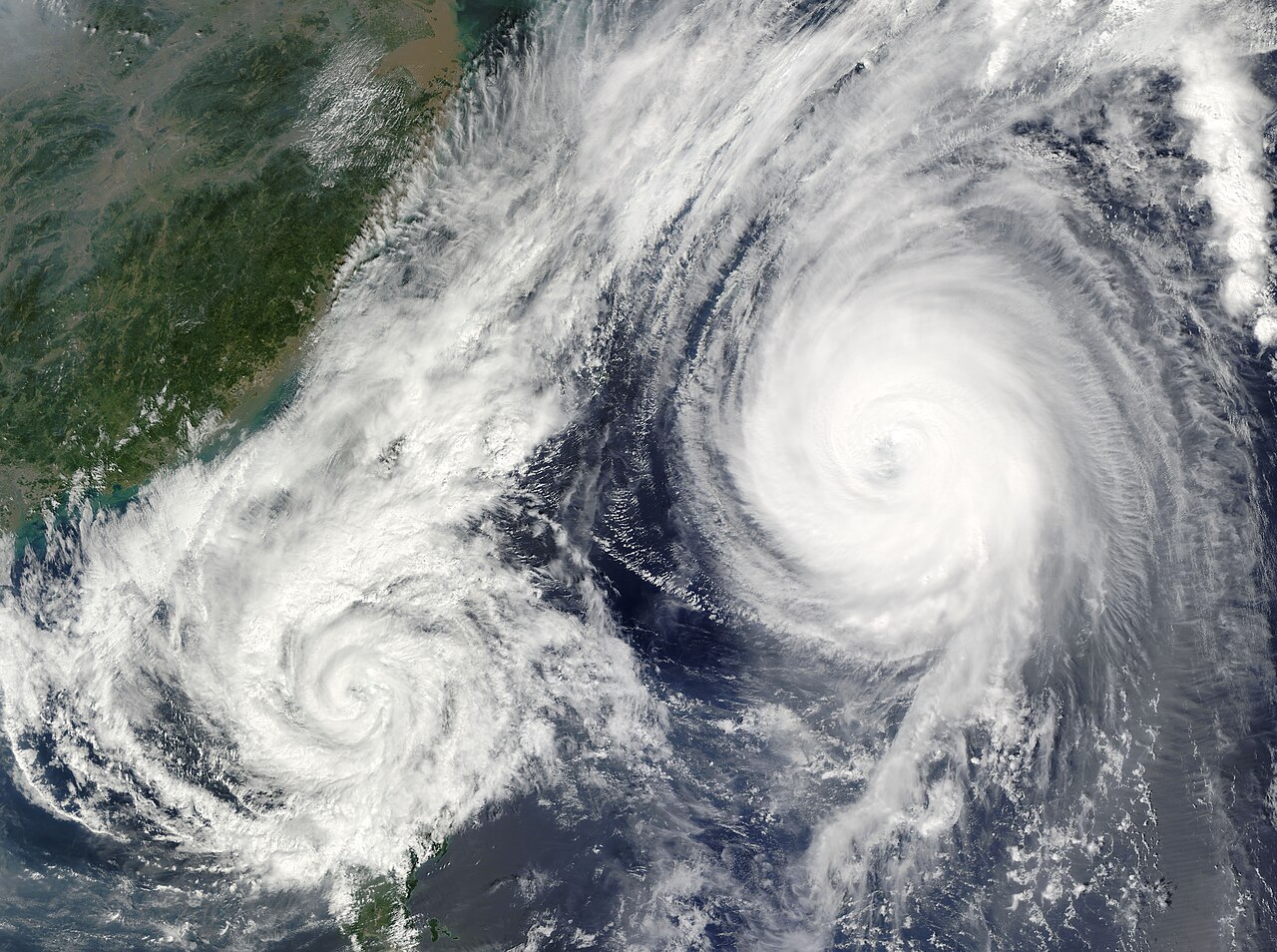 Satellite view of two large, swirling cyclones interacting over the ocean, demonstrating the Fujiwhara Effect. Satellite view of two large, swirling cyclones interacting over the ocean, demonstrating the Fujiwhara Effect.
