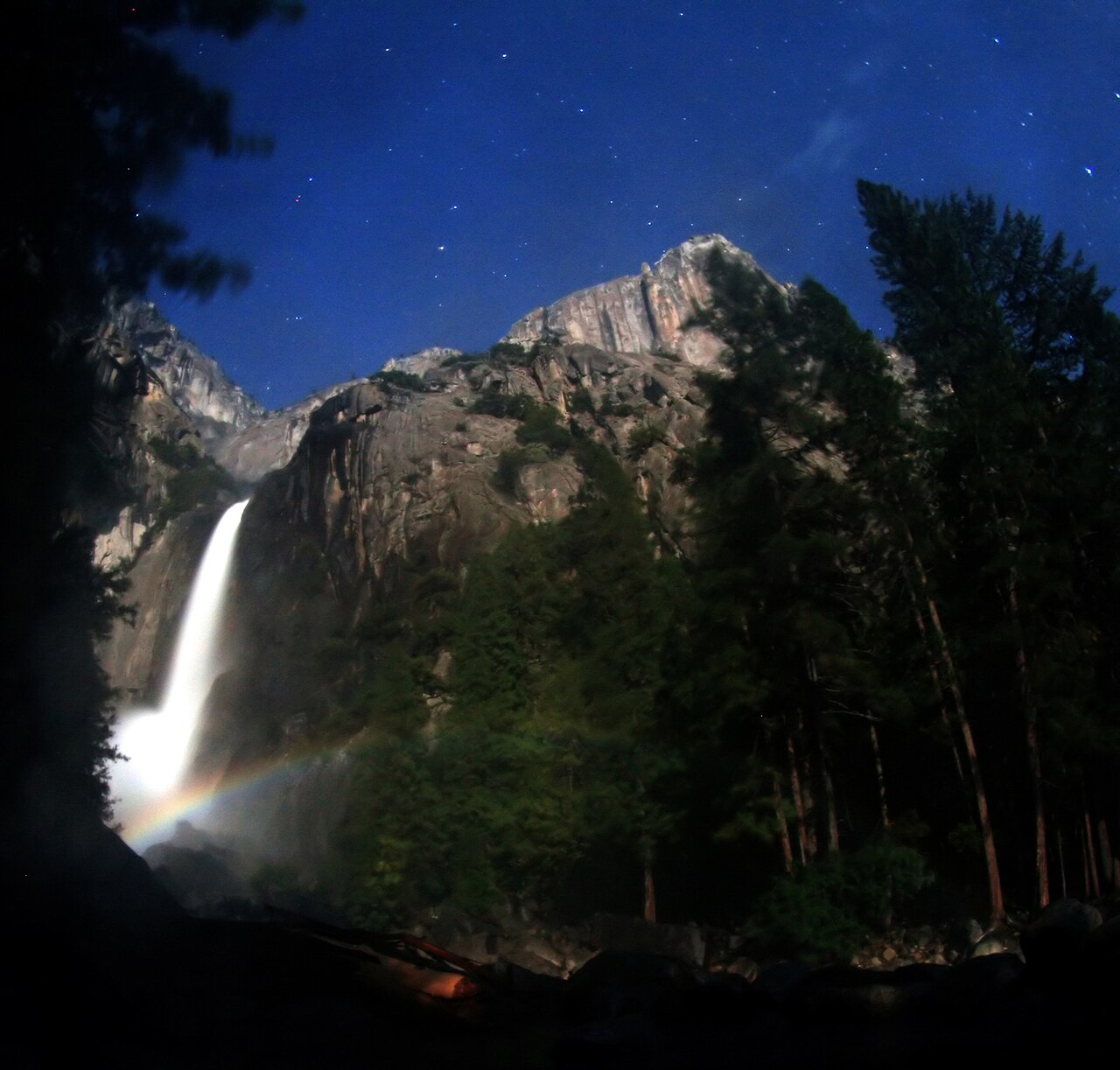 Vibrant moonbow at the base of a waterfall under a starry night sky, illustrating conditions for seeing a moonbow. Vibrant moonbow at the base of a waterfall under a starry night sky, illustrating conditions for seeing a moonbow.